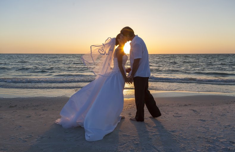A bride and groom on a beach.