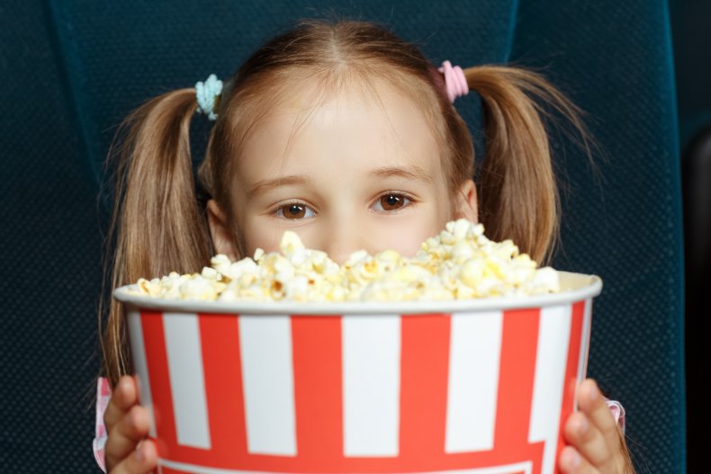 A girl holding a bucket of popcorn.