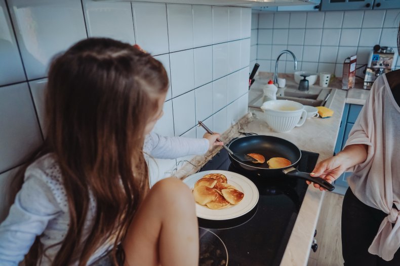 A young girl cooking with her mom.