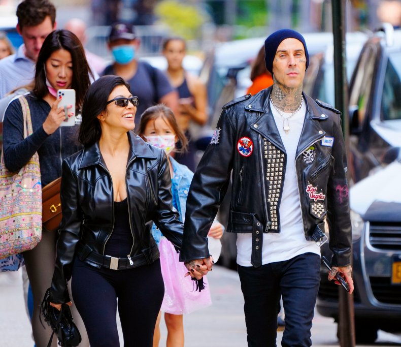 Kourtney Kardashian and Travis Barker walk hand-in-hand.