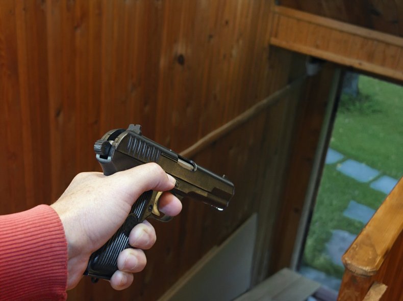 A man pointing a gun outside.