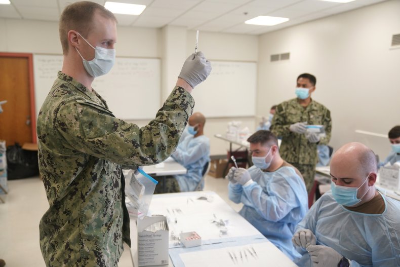 Navy personnel prepare doses of COVID vaccine