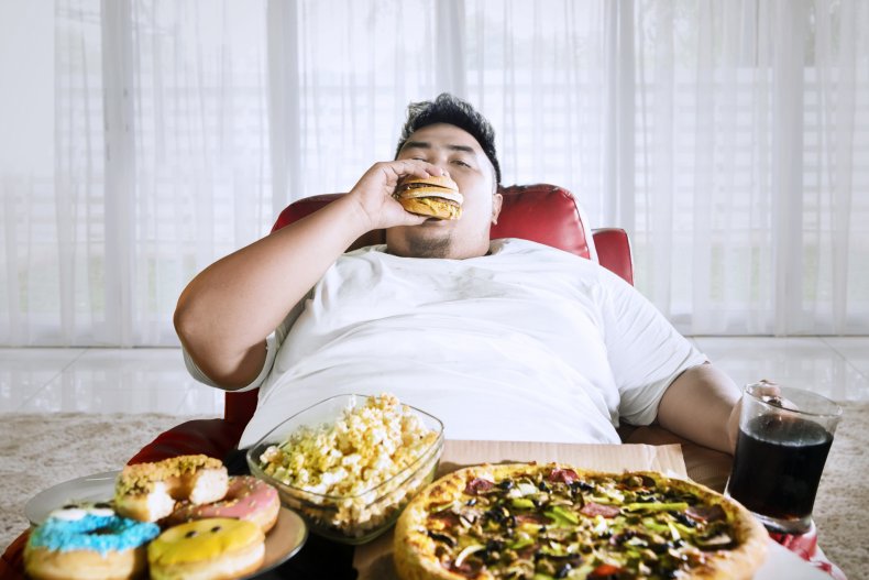An obese man eating junk food.