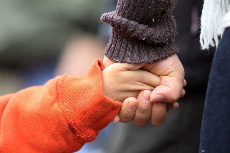 A parent holds their child's hand