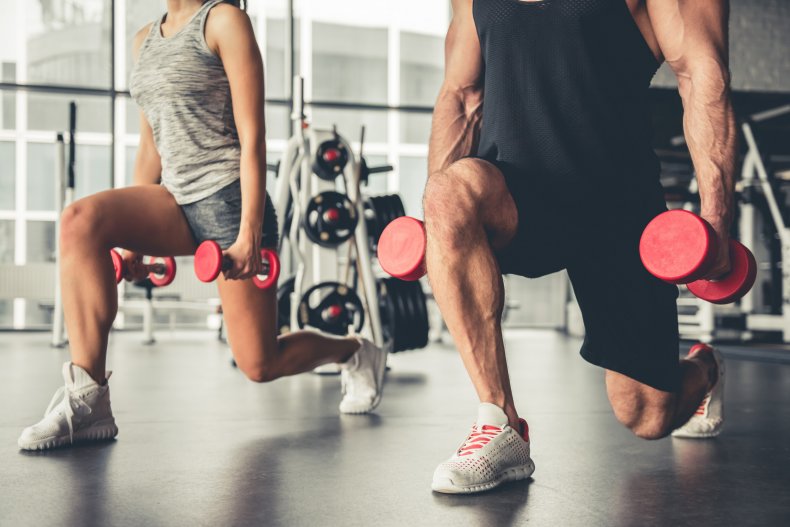 Two people using dumbbells at a gym.