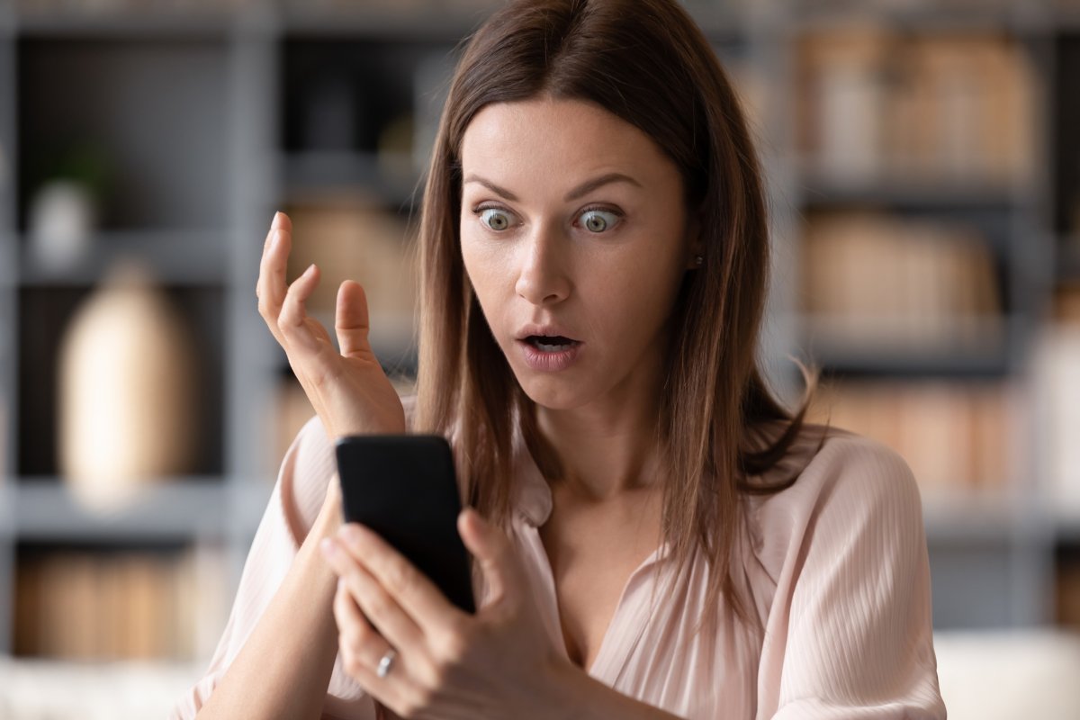A woman looking shocked at her phone.