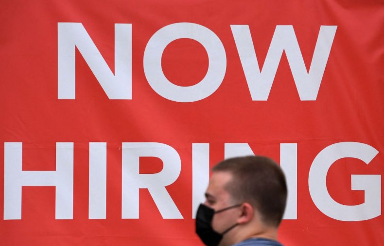 A man walks past "Now Hiring"
