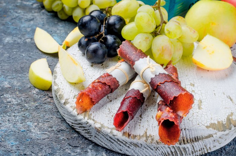 Rolls of fruit leather and fresh fruit.