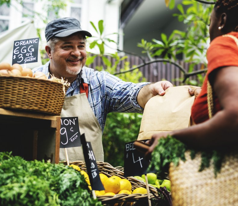 Greengrocer hands a bag to customer.