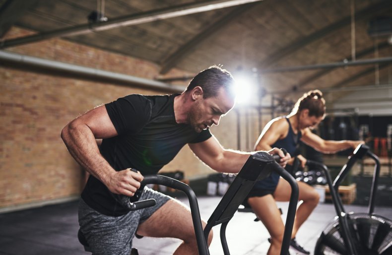 People exercising on a bicycle machine. 