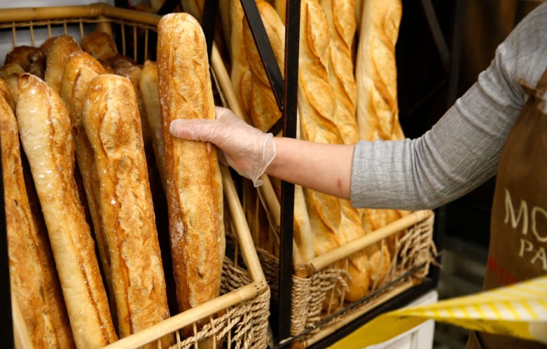 A baker holds a freshly baked baguette
