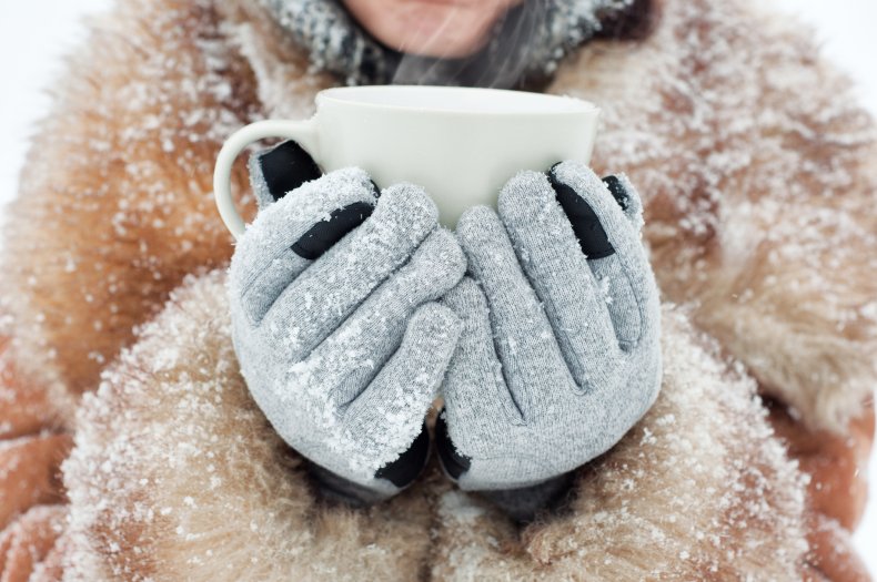 Person holding mug in snow