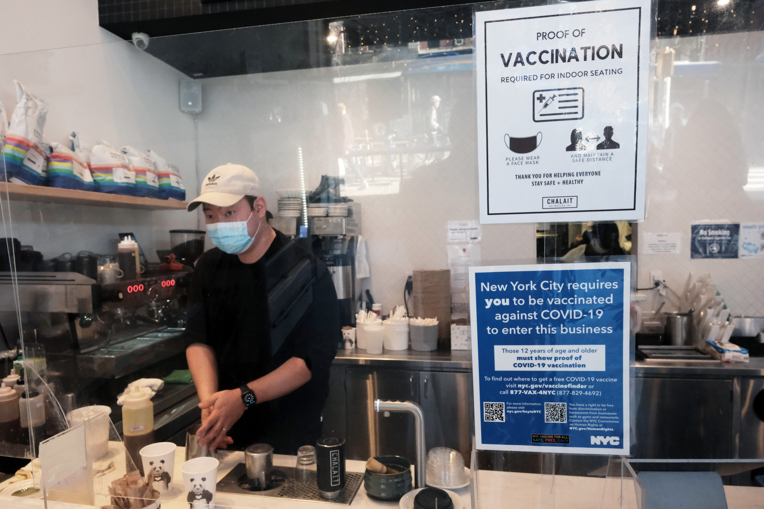 masked employee works nyc coffee shop