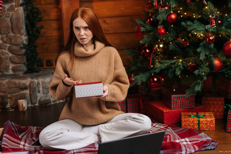 An unhappy woman opening a Christmas present.