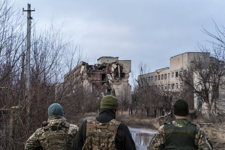 Ukrainian soldiers walk past destroyed buildings
