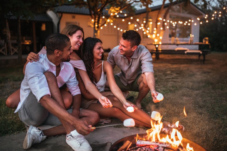 People toasting marshmallows over a backyard campfire.