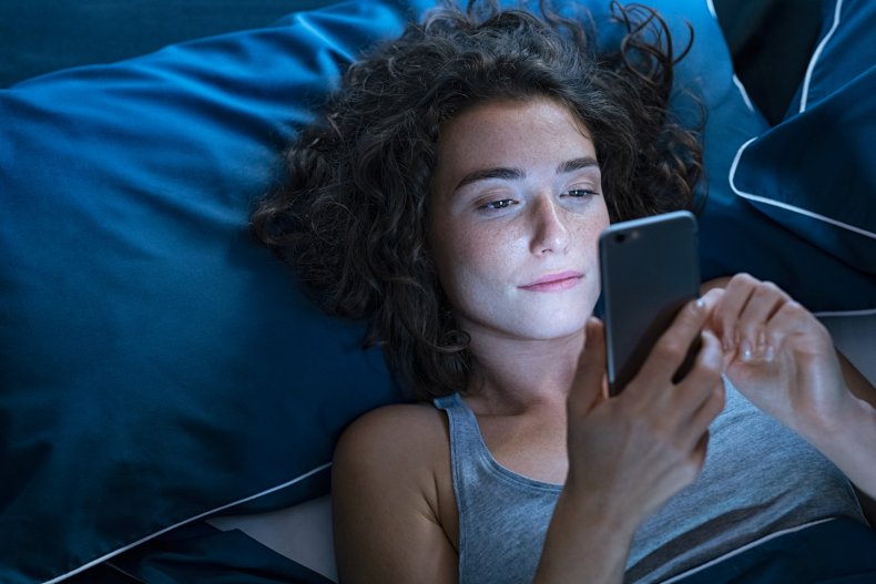 A woman using her phone in bed.