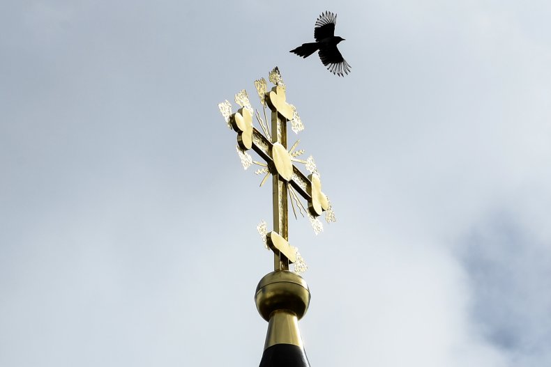 A bird flies over cross