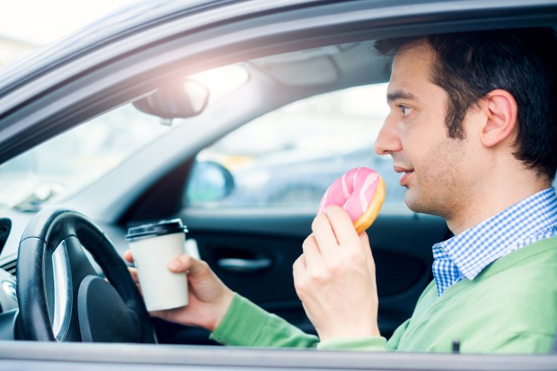 A motorist eating a donut.