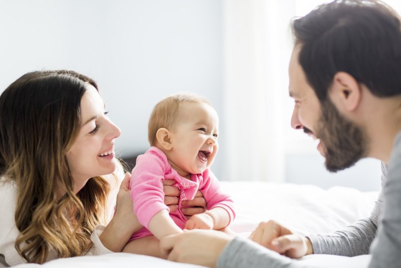 A couple watching a baby laughing.