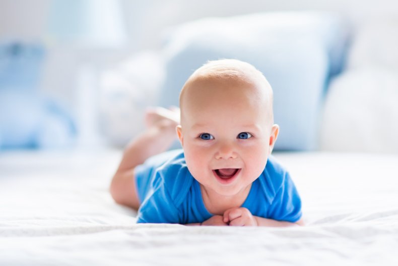 A smiling baby laying on their tummy.