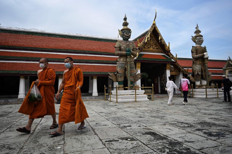 Buddhist monks walk inside the Grand Palace