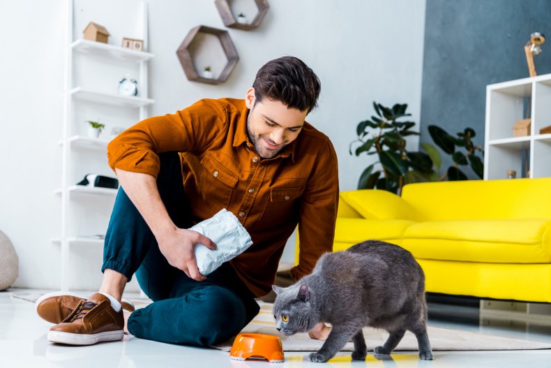 A man is sniffing food with a cat.