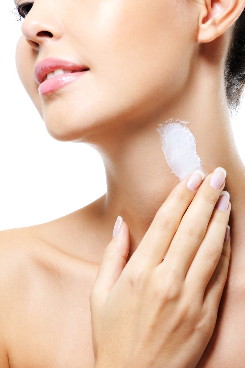 A woman applying cream to her neck.