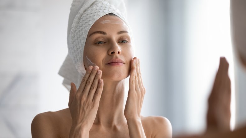 A woman putting lotion on her face.