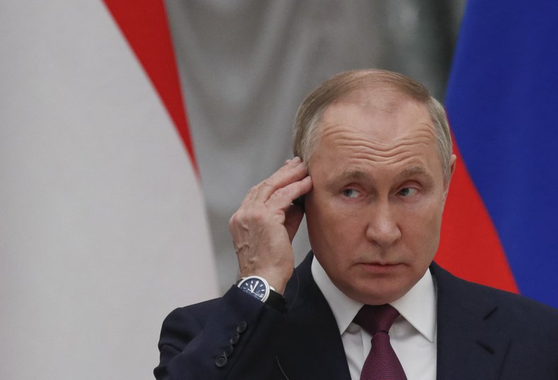 Vladimir Putin stands near Russian flag