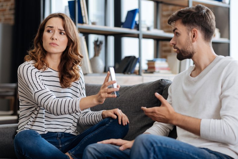 A woman showing a man a phone.