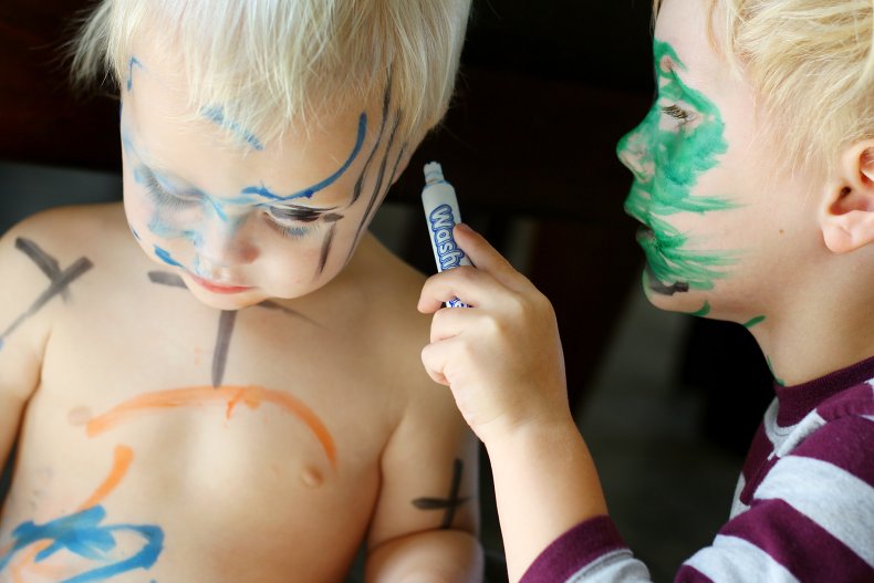 Two kids playing with coloring pens.