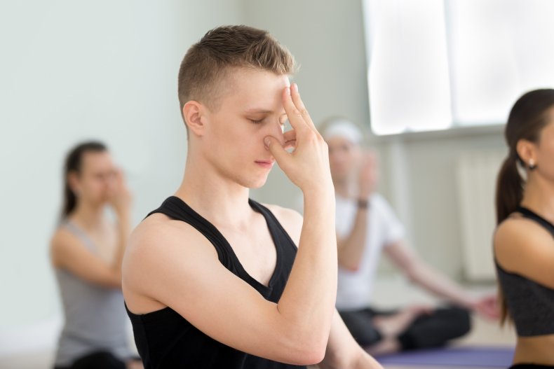 A yoga class doing alternate nostril breathing.