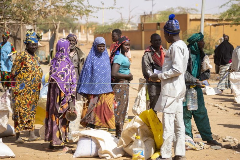 Displaced people wait in line for food