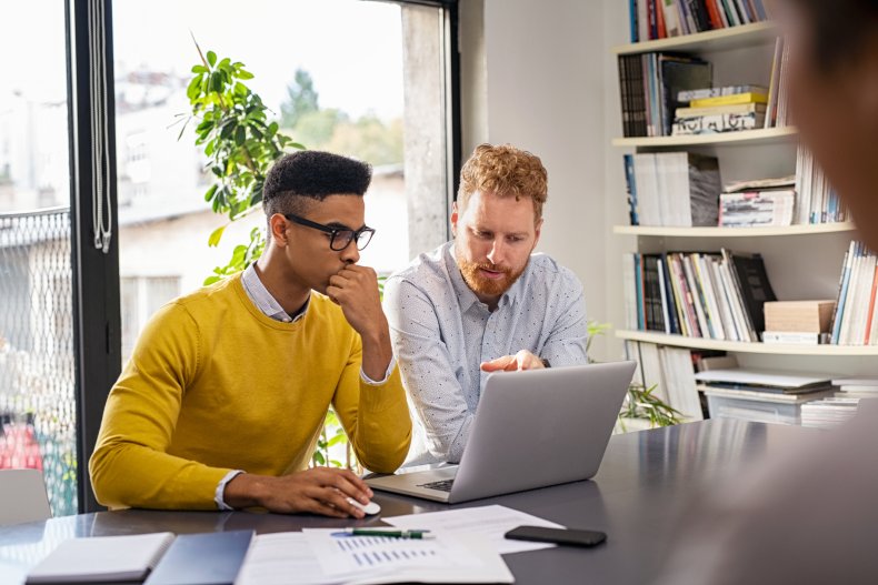 Two men working at a laptop.