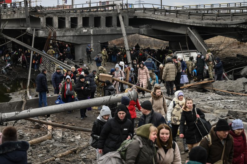 People cross a destroyed bridge in Ukraine