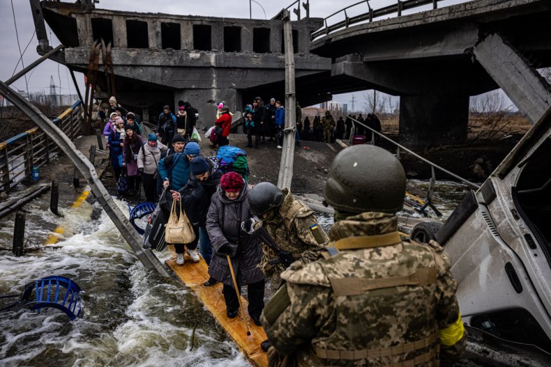 Evacuees cross a destroyed bridge in Irpin