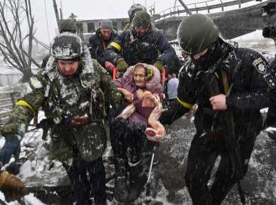 Ukrainian soldiers help an elderly woman 