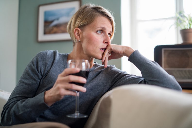 A woman looking anxious while having wine.