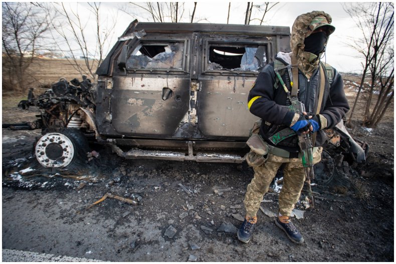 Ukrainian soldier in front of damaged car