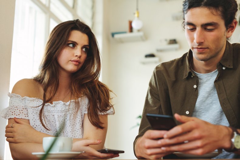 A woman looking a man using phone.