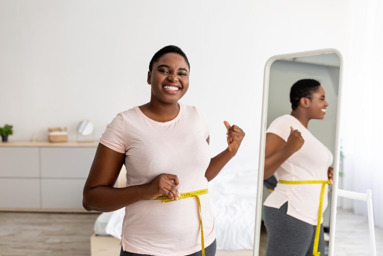 Plus size woman measuring waist with tape