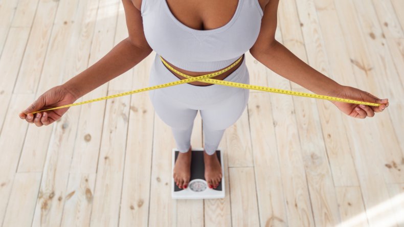 A lady measuring her waist with tape