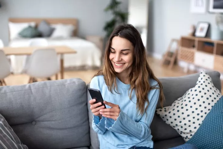 A smiling woman looking at her cellphone. BESTFORYOU/STOCK.ADOBE.COM