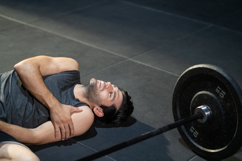 A man laying on mat holding arm.