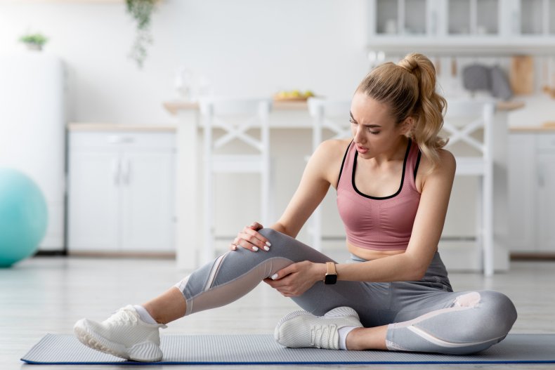 A woman massaging leg muscle on mat.