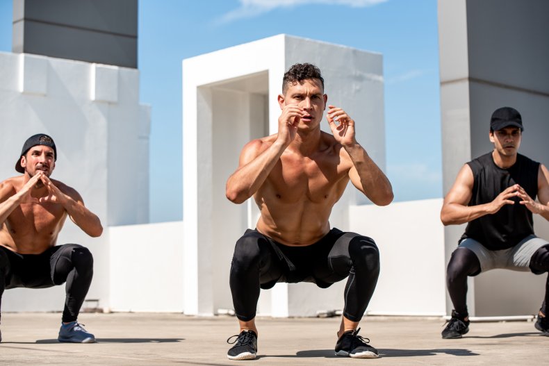 Men doing squat exercises outdoors.