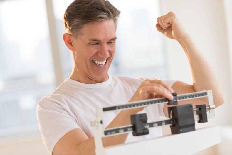 A man looking happy on weight scale.