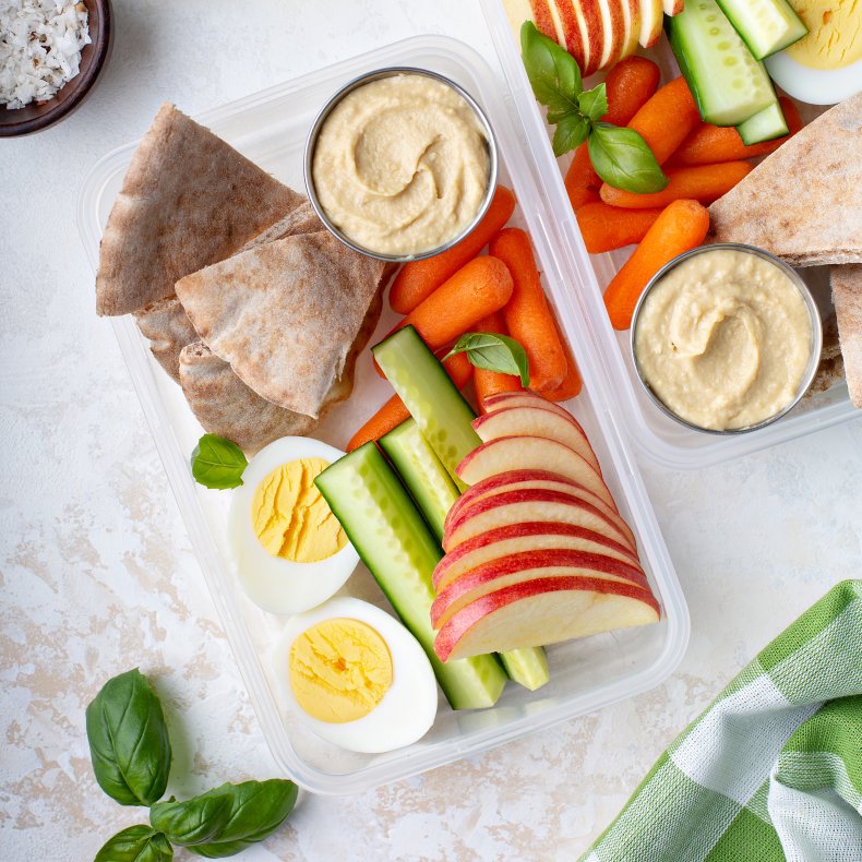 A snack box with vegetables, hummus, pita.