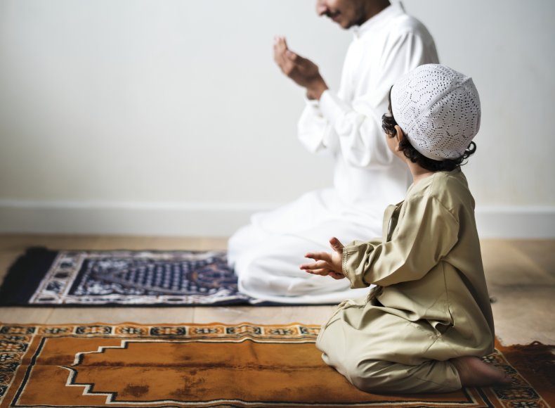 Little boy praying alongside his father during